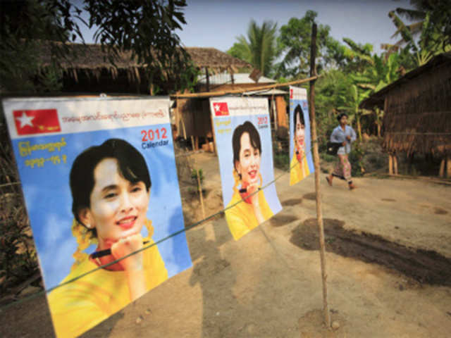 A girl walks past portraits of Aung San Suu Kyi