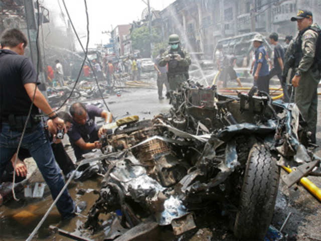 Thai bomb squad members inspect the wreckage of car 