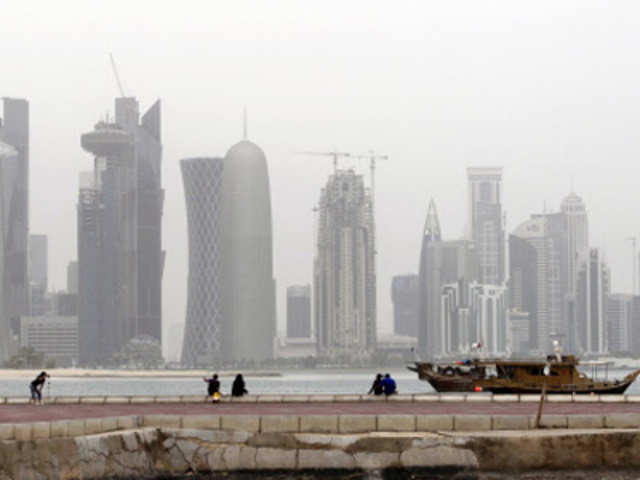 A traditional wooden fishing dhow in port overlooking buildings on the Doha skyline