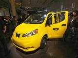 Journalists and observers surround the Nissan NV200 