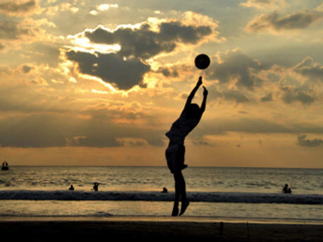 An Acehnese youth tries to catch a ball on the Loknga beach during sunset in Banda Aceh
