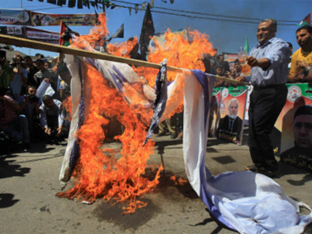 Palestinian protesters burn an Israeli flag