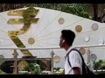  A man walks past an installation of the Rupee logo and Indian currency coins outside the Reserve Bank of India (RBI) headquarters in Mumbai