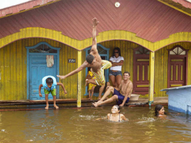 Children swim in front of their home flooded by the rising Rio Solimoes in Anama