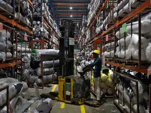 FILE PHOTO: A worker moves rolls of fabric in a forklift in a garment manufacturing unit on the outskirts of Ahmedabad