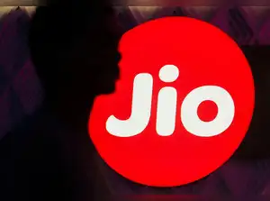 A man walks past Reliance Industries Jio telecoms logo on a street in Mumbai