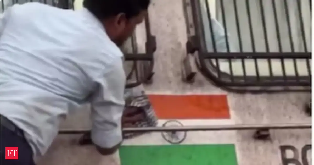Railway worker cleans Indian flag painted on dusty train engine