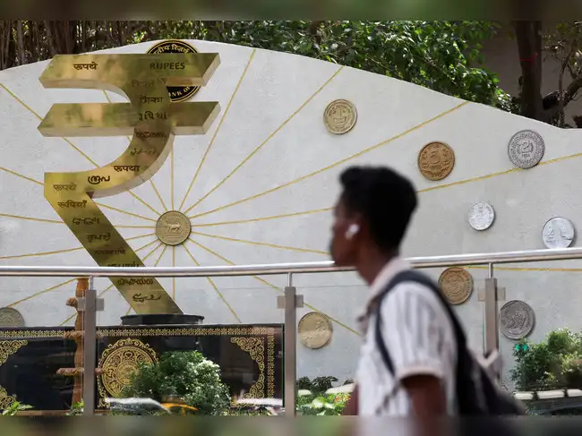 FILE PHOTO: FILE PHOTO: A man walks past an installation of the Rupee logo and Indian currency coins outside the Reserve Bank of India (RBI) headquarters in Mumbai
