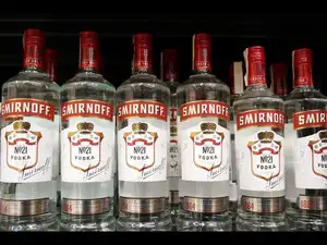 Bottles of Smirnoff vodka are displayed on a shelf in a supermarket