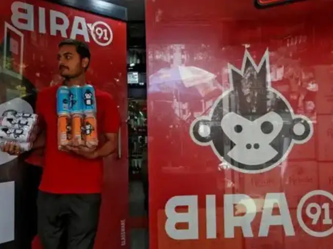 FILE PHOTO: An employee carries Bira beer cans to deliver them to a customer at a liquor store in Mumbai