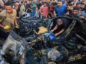 Palestinians inspect the site of an Israeli strike on a vehicle, in Gaza City