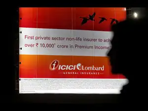 FILE PHOTO: A man walks past a billboard of Indian insurer ICICI Lombard in Mumbai