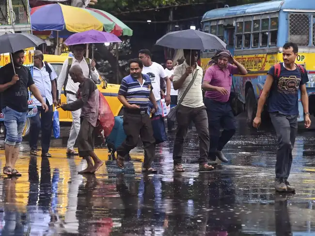 Kolkata: Commuters on a road amid rainfall, in Kolkata.(...