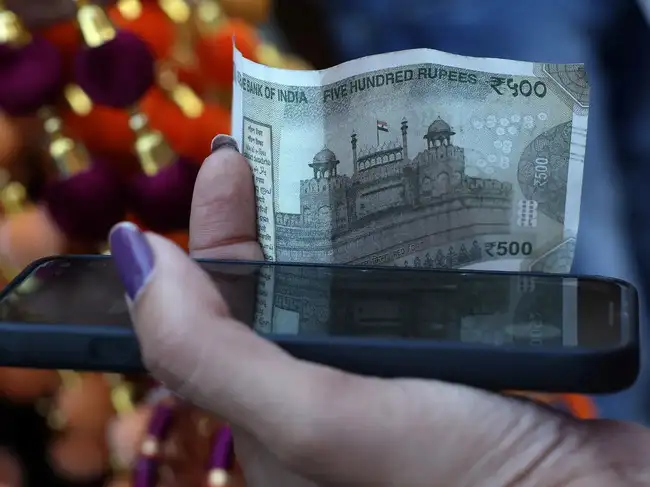 A woman holds a five-hundred-rupee currency note in the old quarters of Delhi