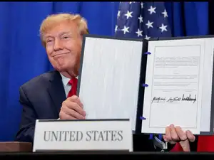 US President Donald Trump shows a signed document as he attends a trilateral signing event with Danish Prime Minister Mette Frederiksen (not pictured) and Greenland Prime Minister Jens-Frederik