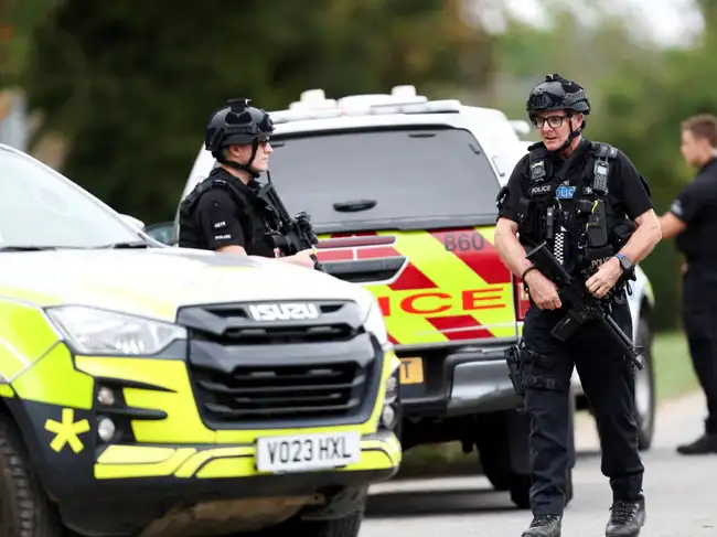 Armed police officers work on a road outside the perimiter of the RAF Fairford airbase, after police declared a major incident at the base after several men were arrested on suspicion of offences