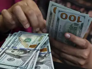 Banks seeks clarification on implementation of RBI forex measures - A teller counts U.S. dollar bank notes at a money changer