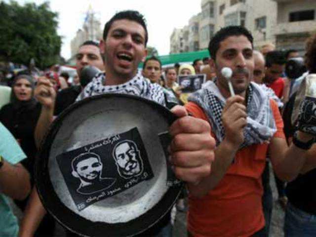 Protestors bang on pots covered in pictures of Palestinian prisoners