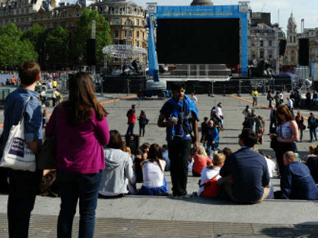 People watch a huge screen being set up at Trafalgar Square