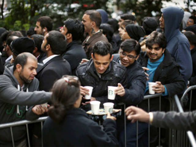 People are given cups of coffee as they queue up in Hanover Square in London