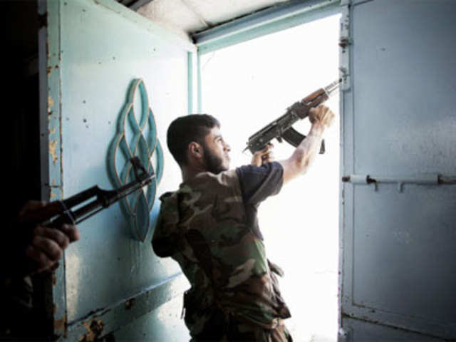 A Free Syrian Army fighter fires his weapon during clashes with government forces