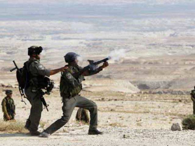 An Israeli border police officer fires tear gas towards Palestinian activists