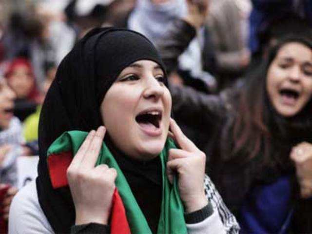 A woman holds a Palestinian flag as she shout slogans against Israel military in Gaza