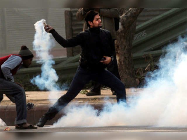 Demonstrator throws a tear gas canister during protest