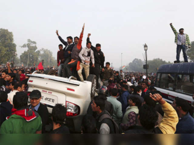 Demonstrators stand atop an overturned government vehicle