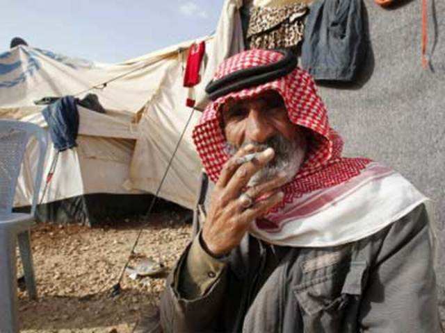 A Syrian refugee smokes outside his tent at the Al Zaatri refugee camp
