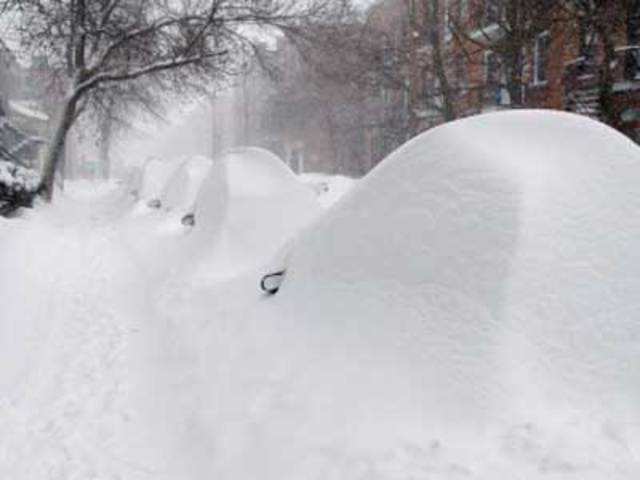Parked cars hide under mounds of snow