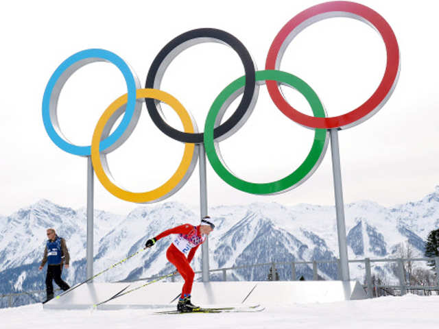 Dario Cologna competes by the Olympic rings in Men's Cross-Country Skiing