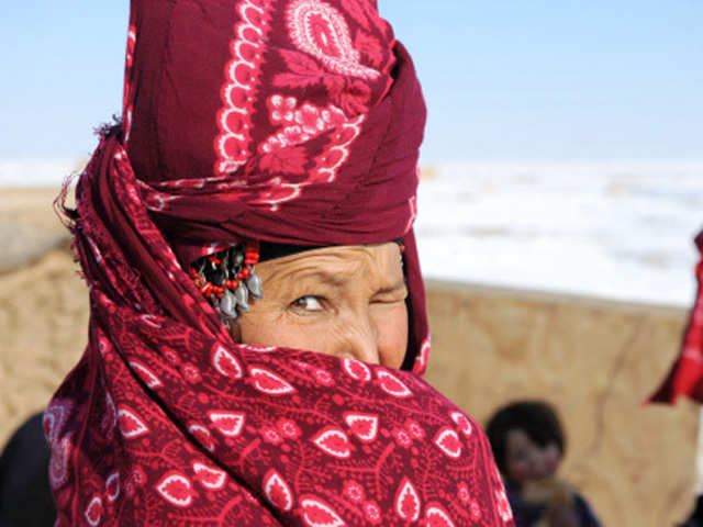 An Afghan internally displaced woman covers her face