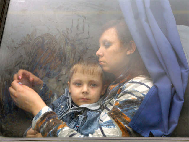 Ukrainian civilians ook at the remains of army truck