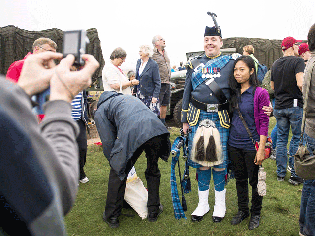 A woman poses with a bagpiper on the Ginkelse Heide, near Ede, the Netherlands