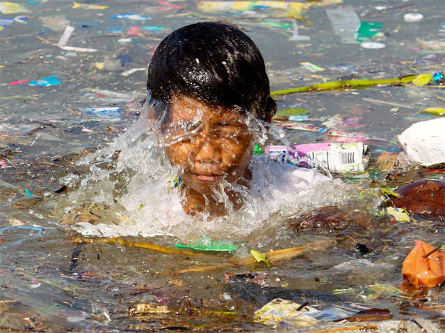 A boy swims amid garbage
