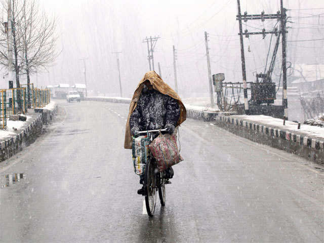 A man riding a bicycle in snowfall