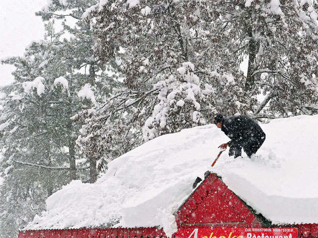A man clearing the roof top in Tangmarg