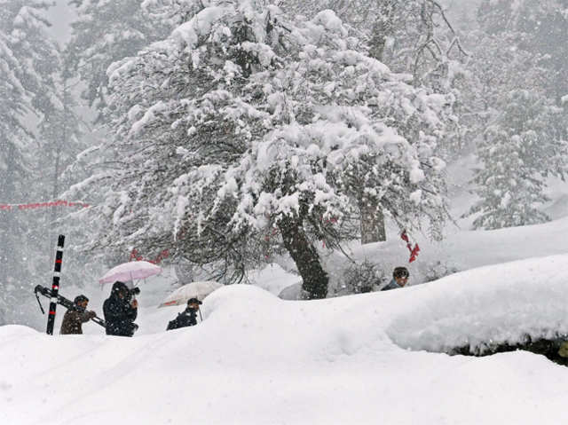 Tourists walk through snow on Gulmarg Road