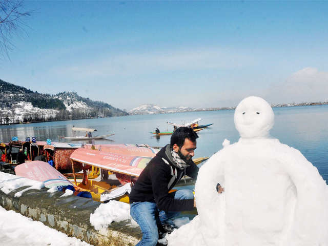 A man makes a snowman at the bank of Dal Lake