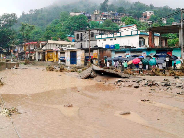 Locals stand near a flooded street