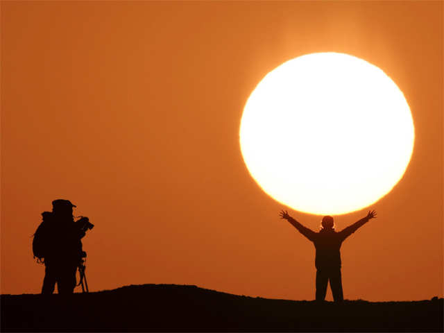 Tourist poses in front of rising sun