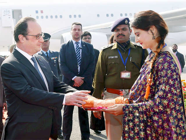 Hollande being presented a shawl on his arrival