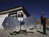 A Tibetan man stands besides a solar energy heating system