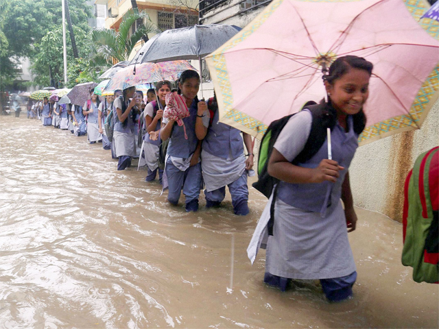 ​School children wade through water logged road