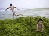A boy sits on a pile of algae 