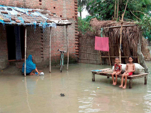 Children sit in front of inundated home