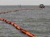 A boat pulls a boom into the Gulf of Mexico