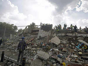 Rescuers, firefighters, policemen, soldiers and volunteers remove rubble and debris from a flattened building in search of survivors after a powerful quake in Mexico City