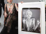 Lady Gaga poses with a large Polaroid picture of herself